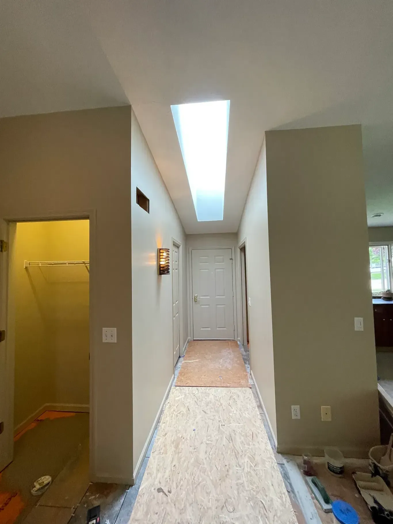 A long hallway in a house with a skylight in the ceiling.
