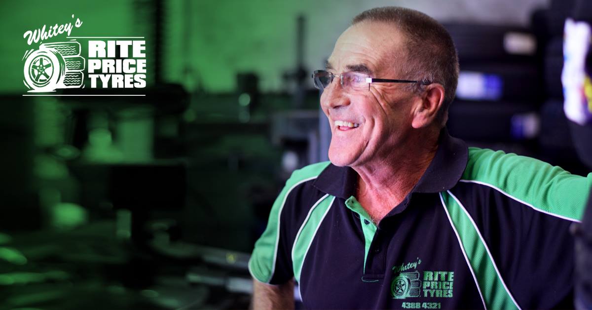 A man wearing glasses and a black and green shirt is smiling — Rite Price Tyres In Berkeley Vale, NSW