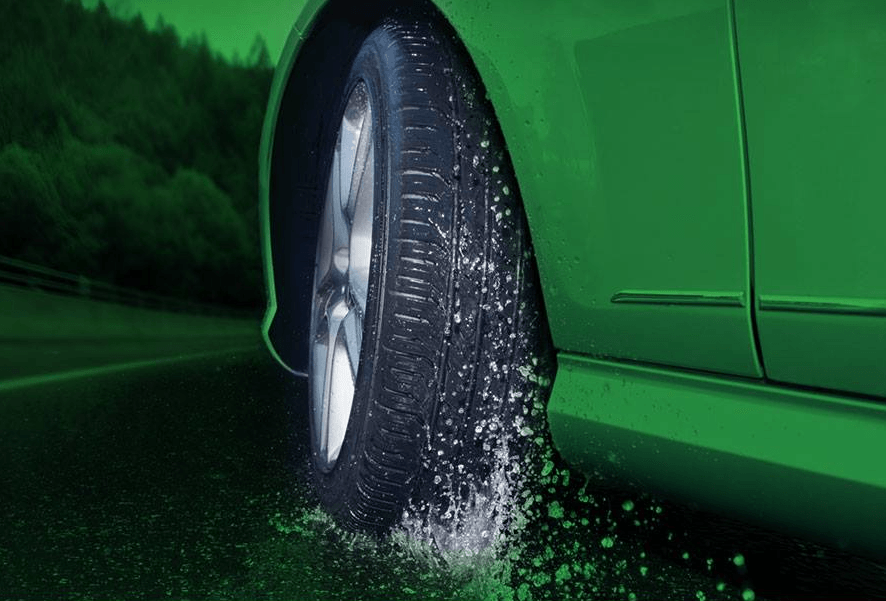 A Green Car is Driving Down a Wet Road — Rite Price Tyres In Berkeley Vale, NSW 