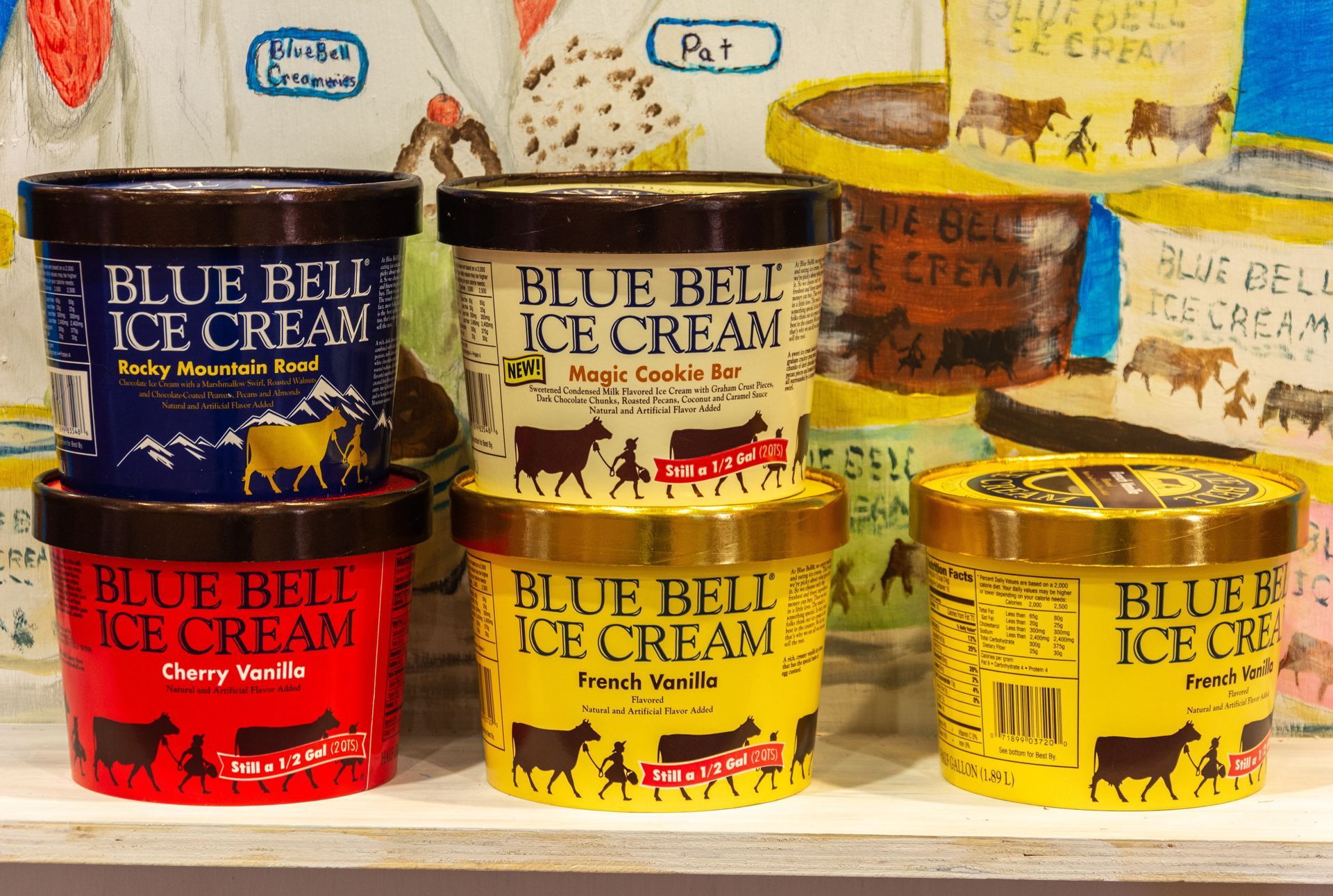 Several tubs of Blue Bell ice cream on display, various flavors.