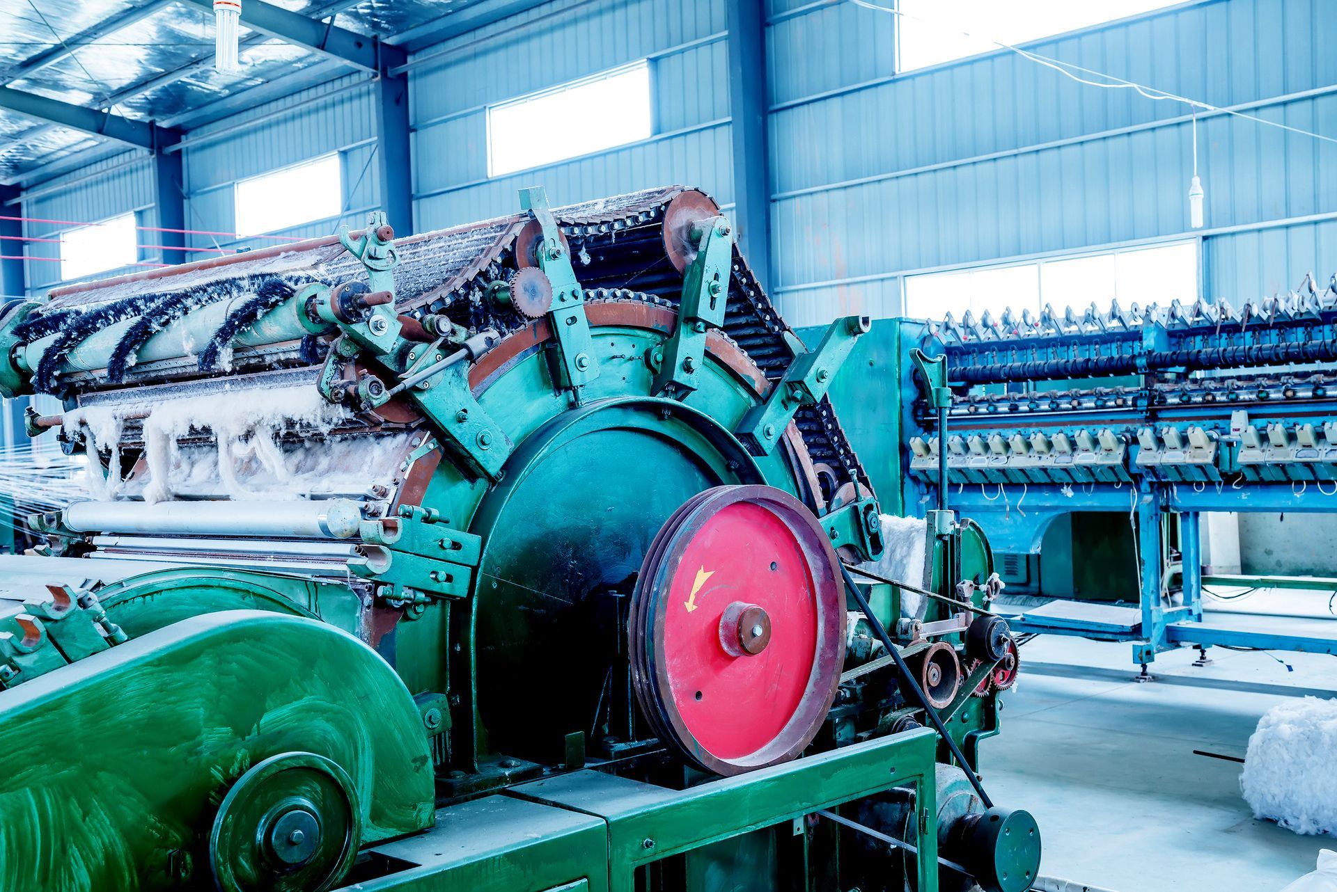 Large industrial machinery in a factory, with a red circular component and turquoise equipment.