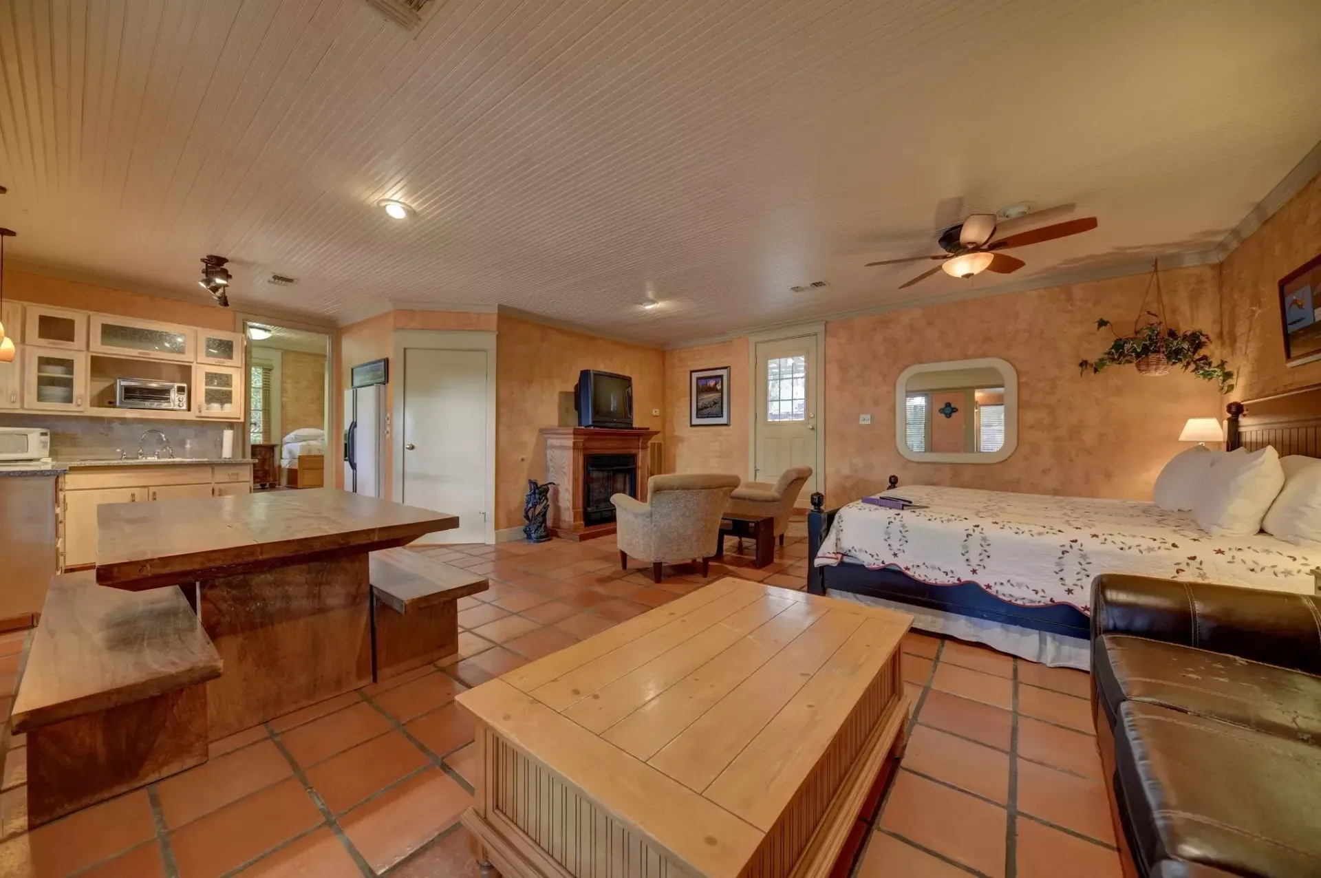 Spacious studio apartment with tile floor, kitchenette, fireplace, bed, seating area, and dining table.