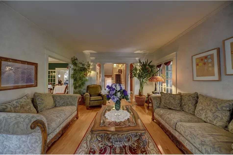 Living room with light-colored sofas, ornate coffee table, and archway to other rooms.