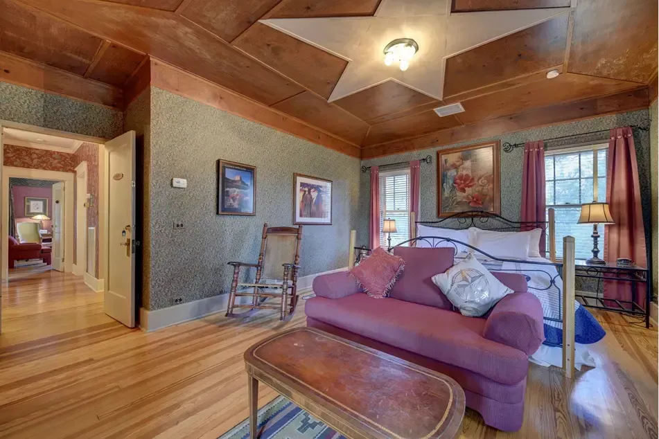 Bedroom with red sofa, bed, hardwood floors, and star-shaped ceiling light.