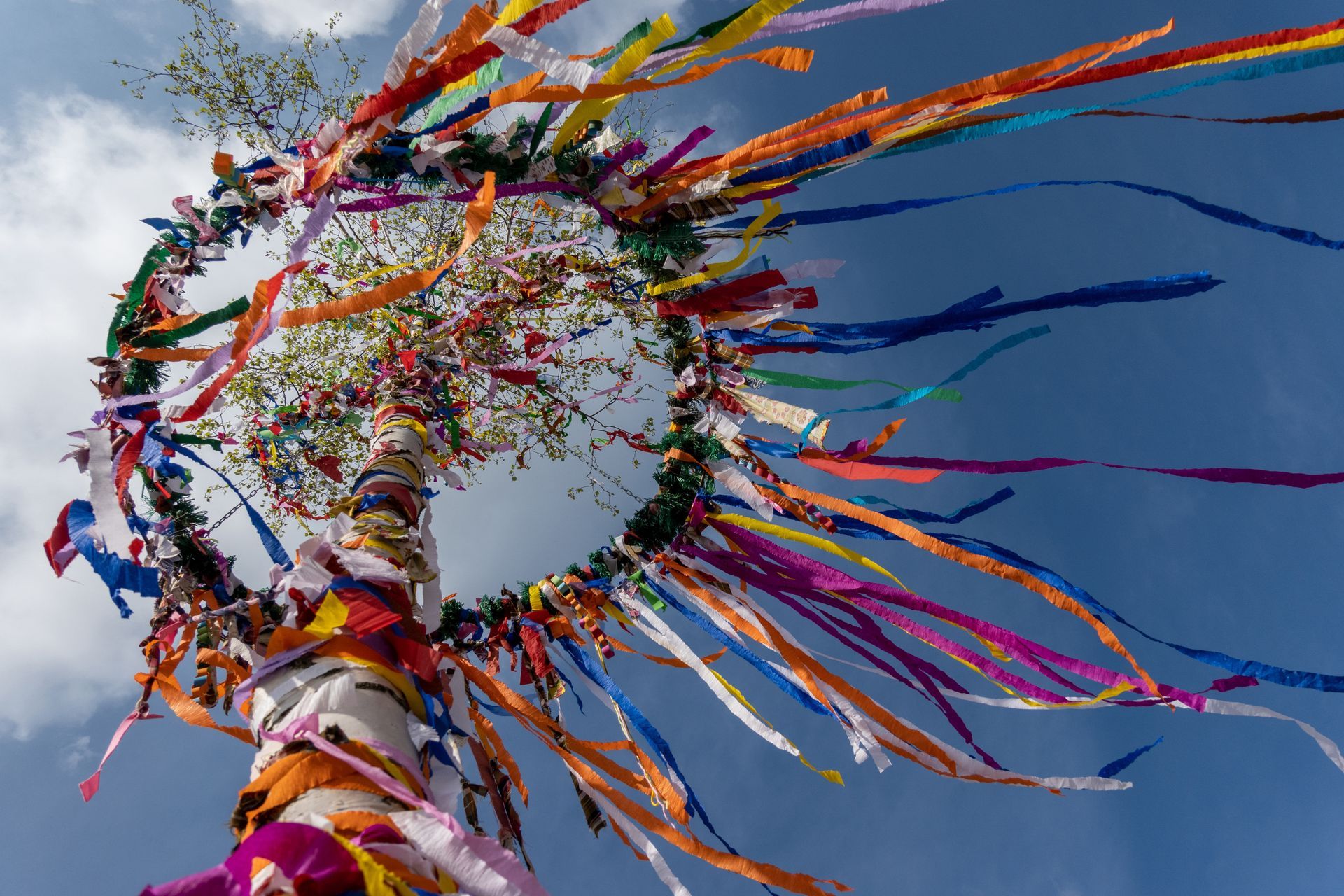 Colorful ribbons blowing from a circular decoration against a clear blue sky