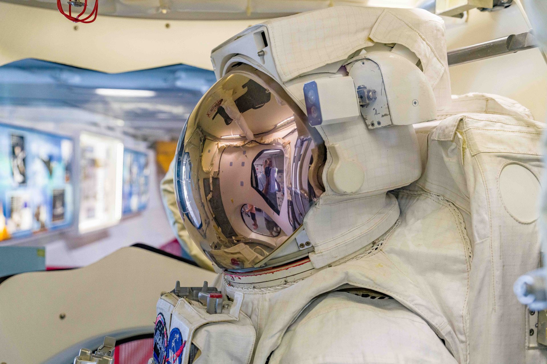 Astronaut in a white spacesuit with reflective visor inside a spacecraft cabin