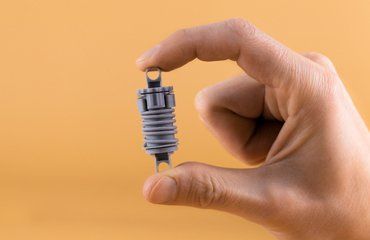 Small grey color assemble part holding by 2 engineer's finger