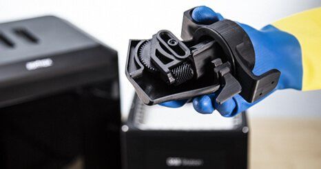 A hand holding a soluble support parts dissolve in Zortrax DSS station