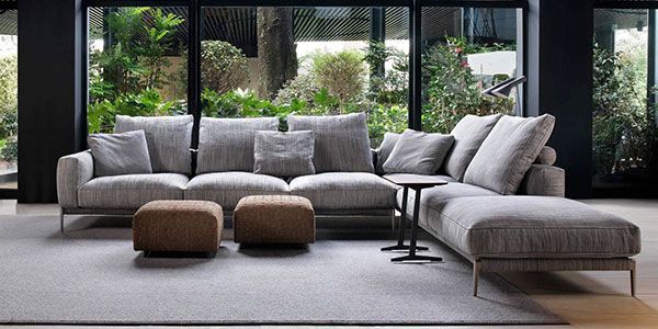 A living room with a large sectional couch and two ottomans.