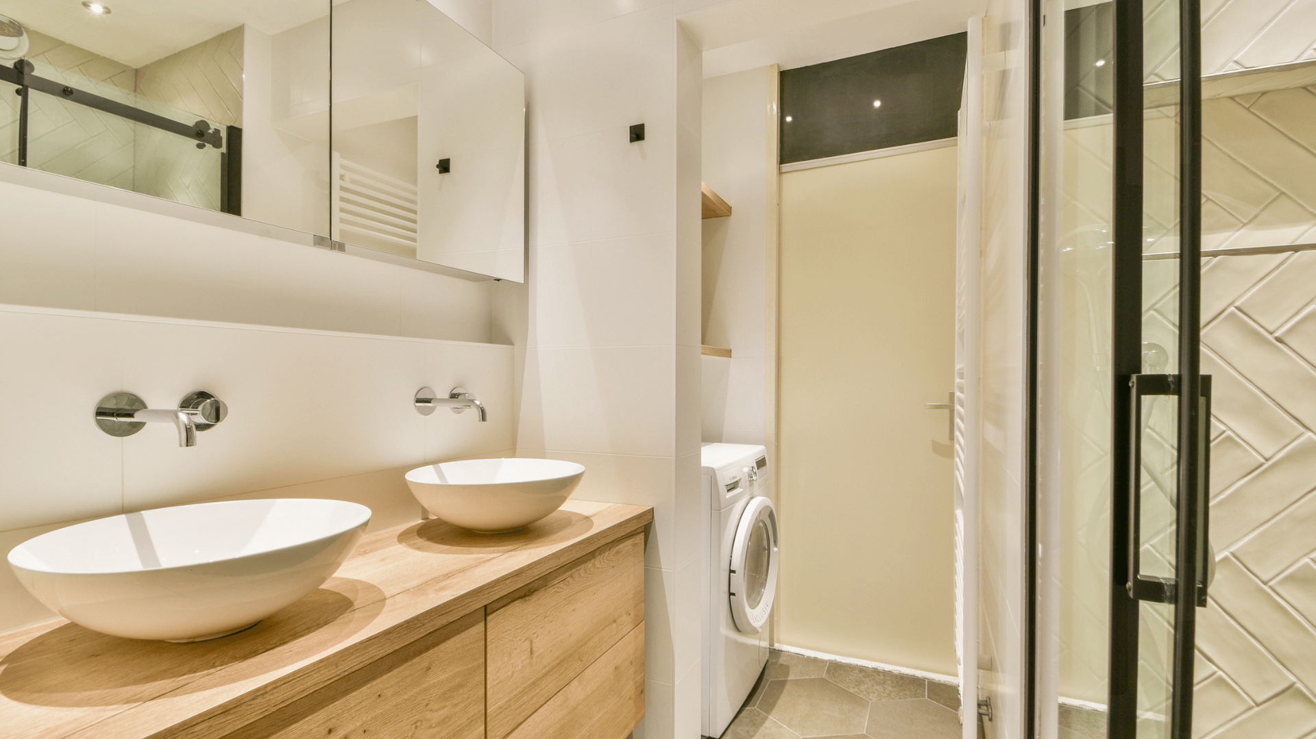 Modern bathroom with two bowl sinks, a washing machine, and a glass shower — Morrison Cabinetry in Cedar Pocket, QLD