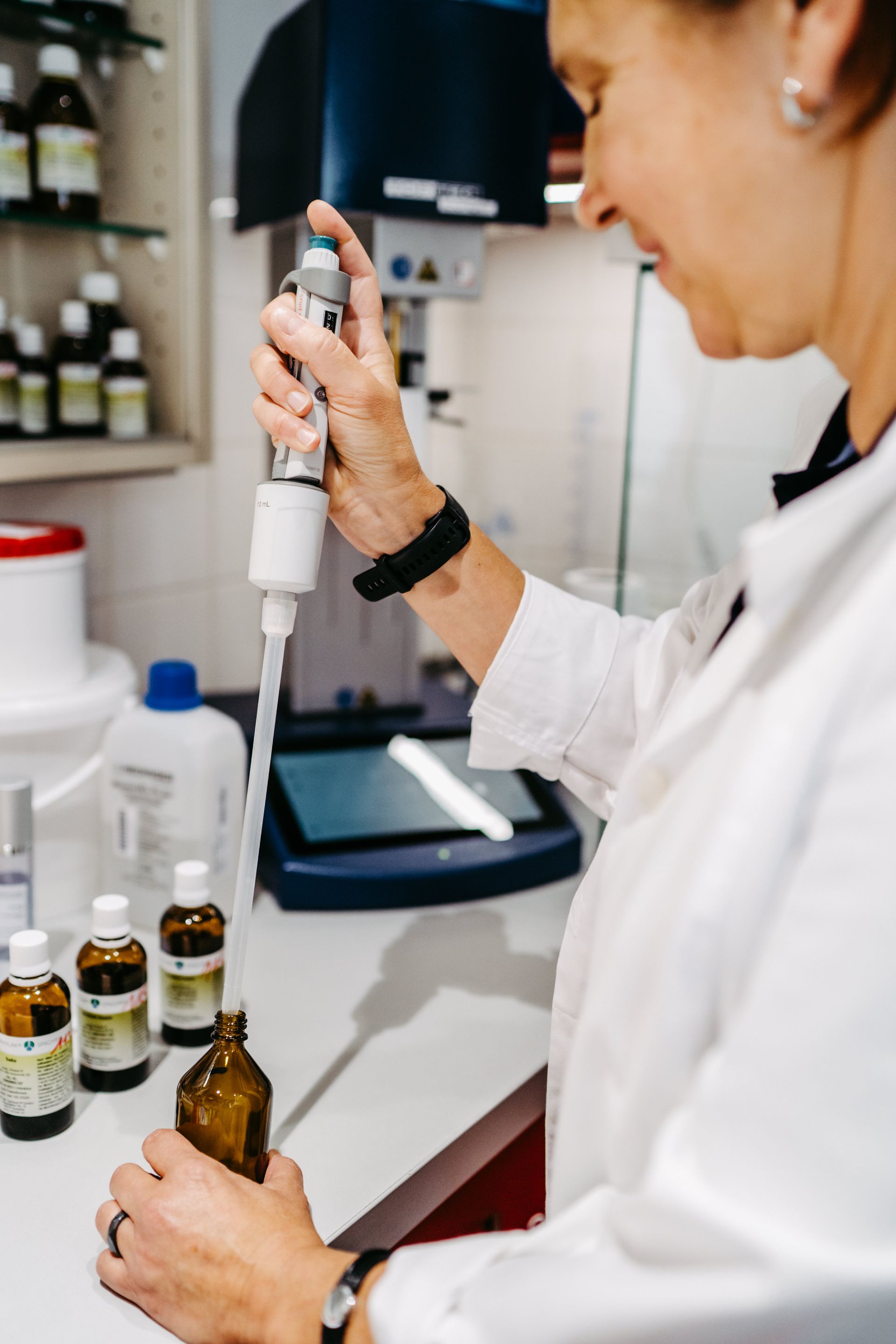 Eine Frau füllt in einem Labor eine Flasche mit einer Pipette.