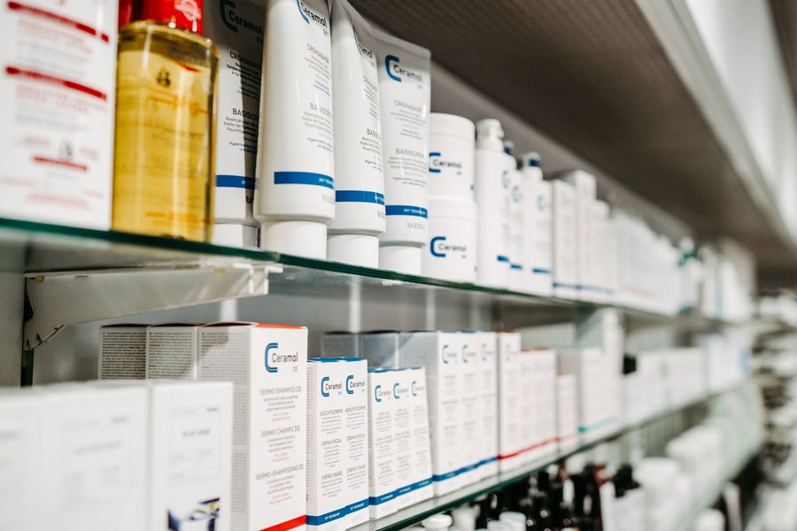 Eine Reihe von Regalen voller Flaschen und Tuben mit Kosmetika in einer Apotheke.