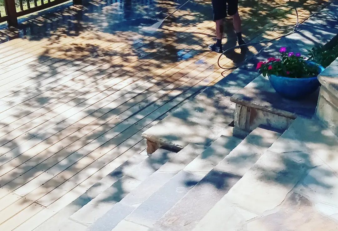 Sunlit stone steps beside a tiled walkway and blue flower pot with pink blooms