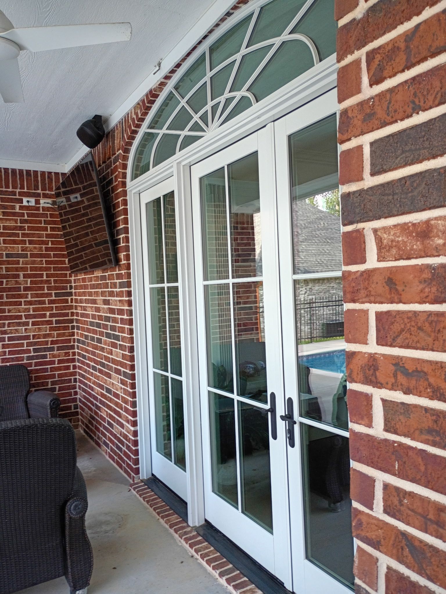 Brick porch with white French doors and arched transom window under a covered ceiling