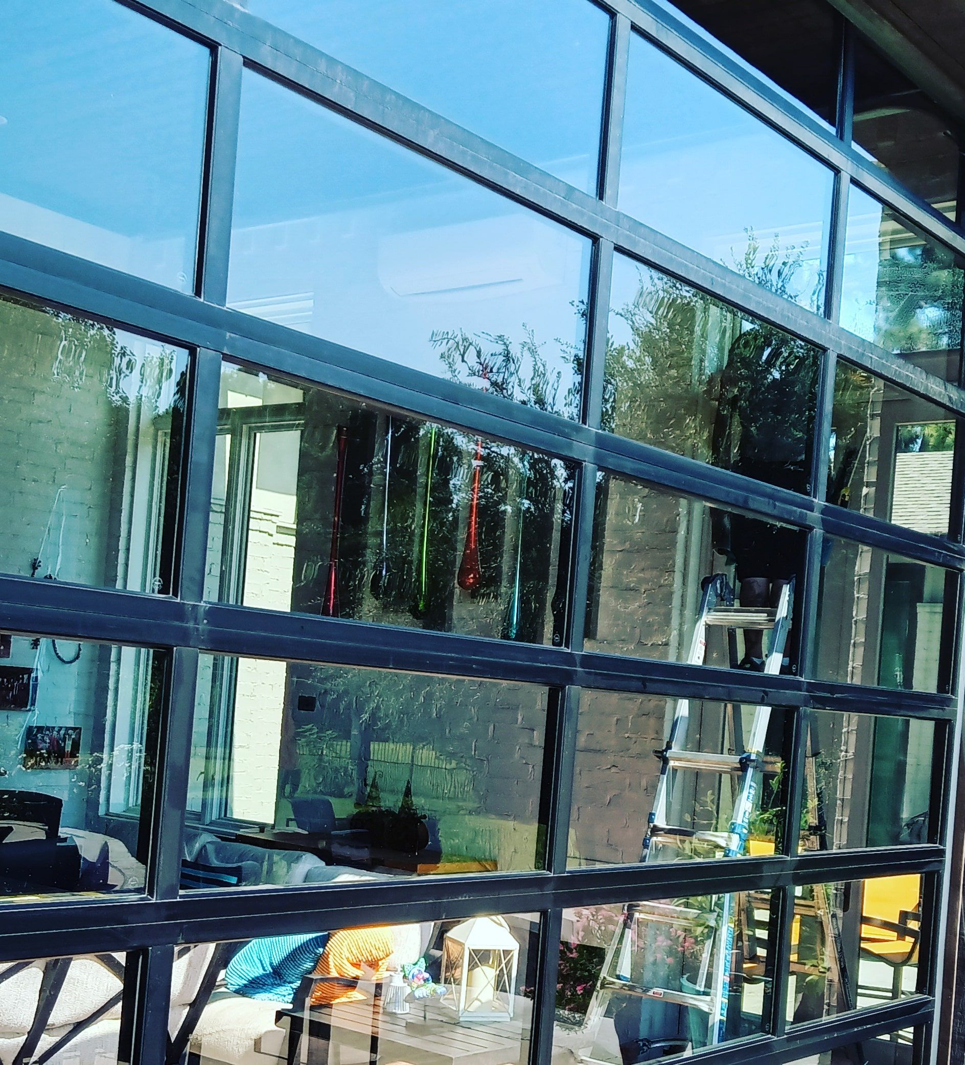Reflective glass building facade with blue sky and trees mirrored in the windows