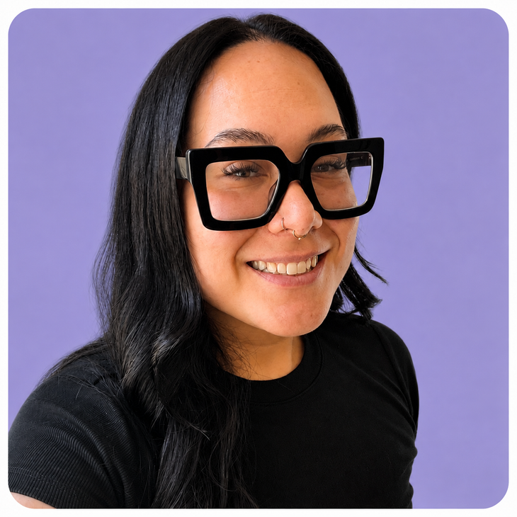 Woman smiling in oversized black glasses against a lavender background