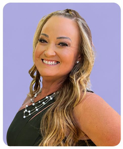 Smiling woman with long blonde hair in a black dress against a lavender background