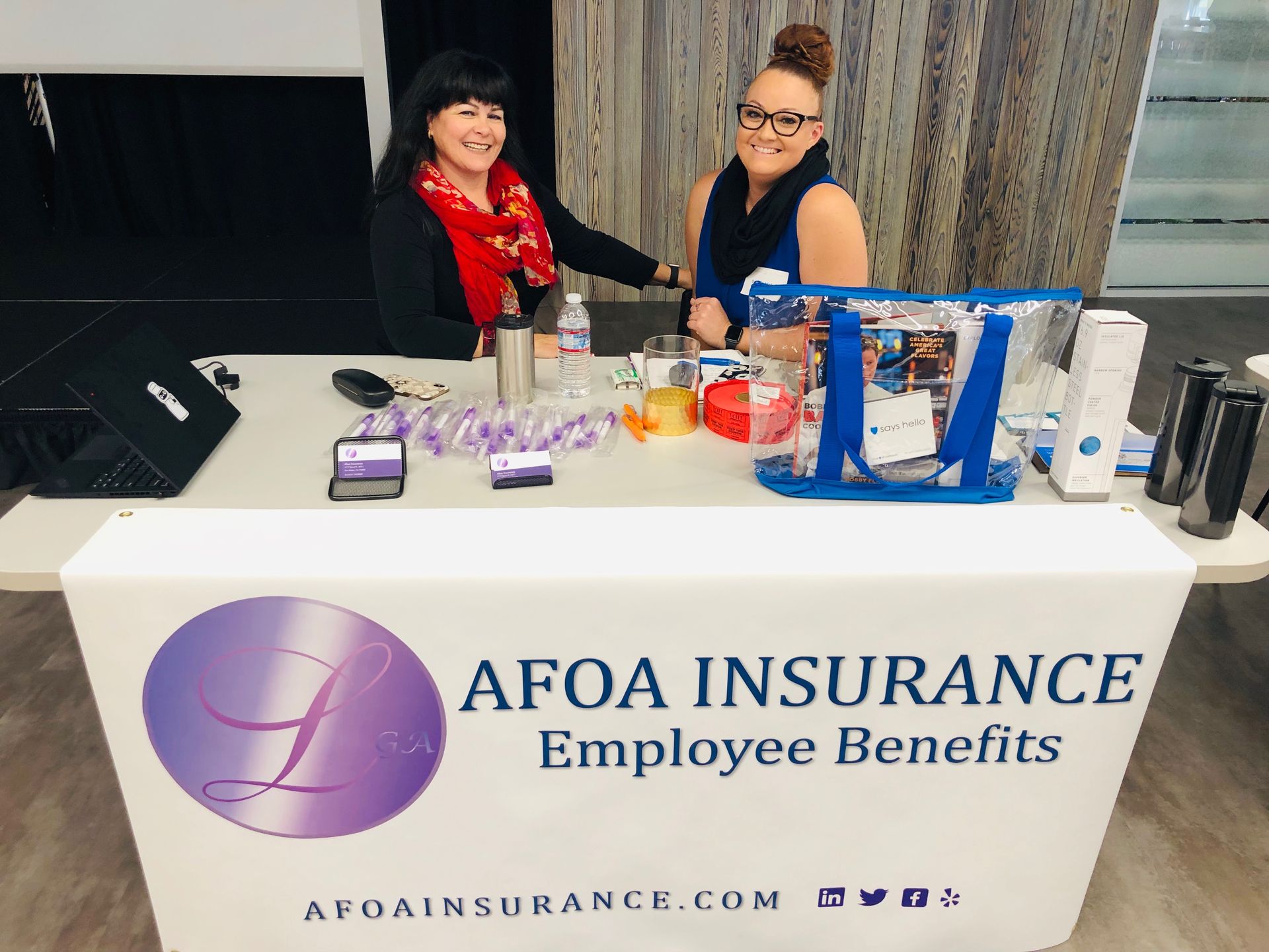 AFOA Insurance benefit table with two smiling representatives and promotional items