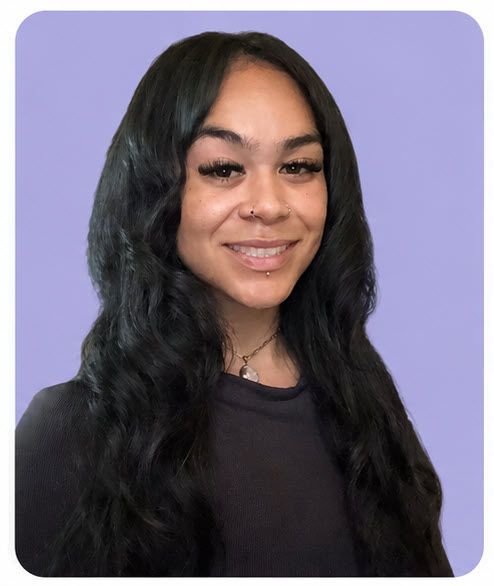 Portrait of a smiling woman with long dark hair against a lavender background