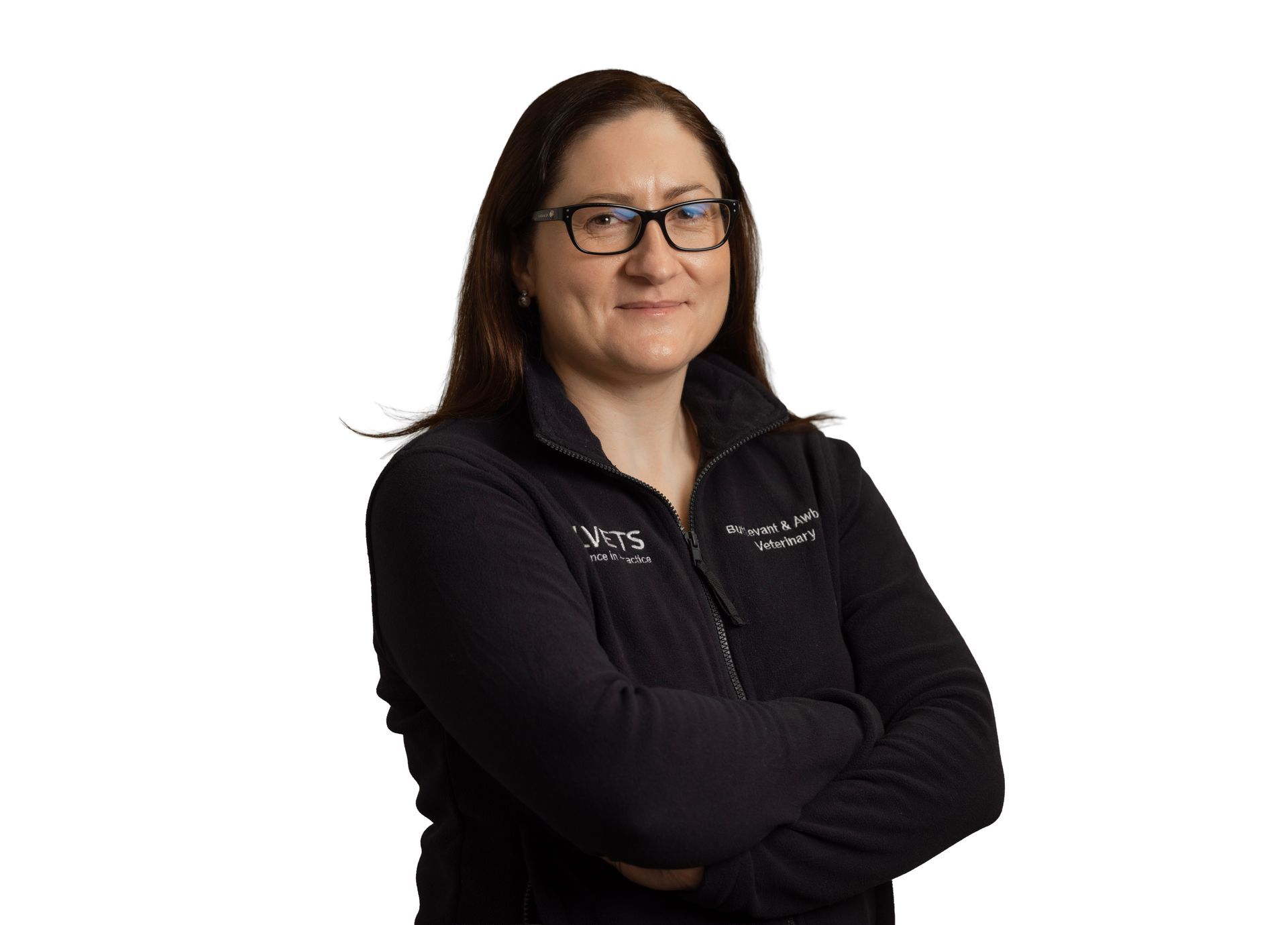 Woman in black glasses and jacket, standing with arms crossed against a white background.