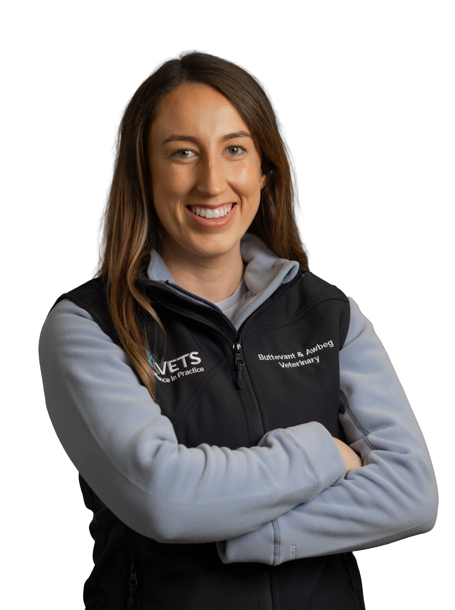 Smiling person with arms crossed, wearing a gray shirt and black vest on a white background