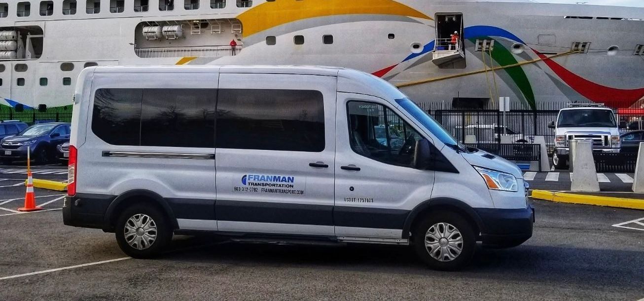 White passenger van parked in front of a cruise ship.