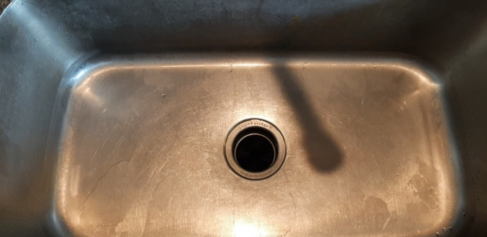A close up of a stainless steel kitchen sink with a drain hole.