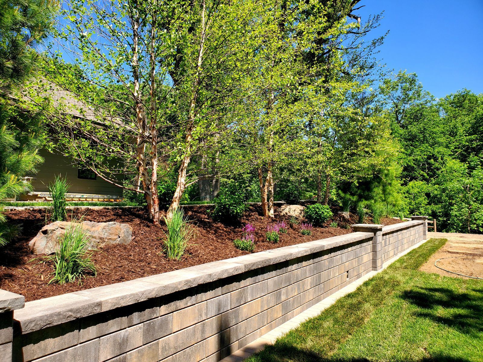 A brick wall is surrounded by a lush green garden.
