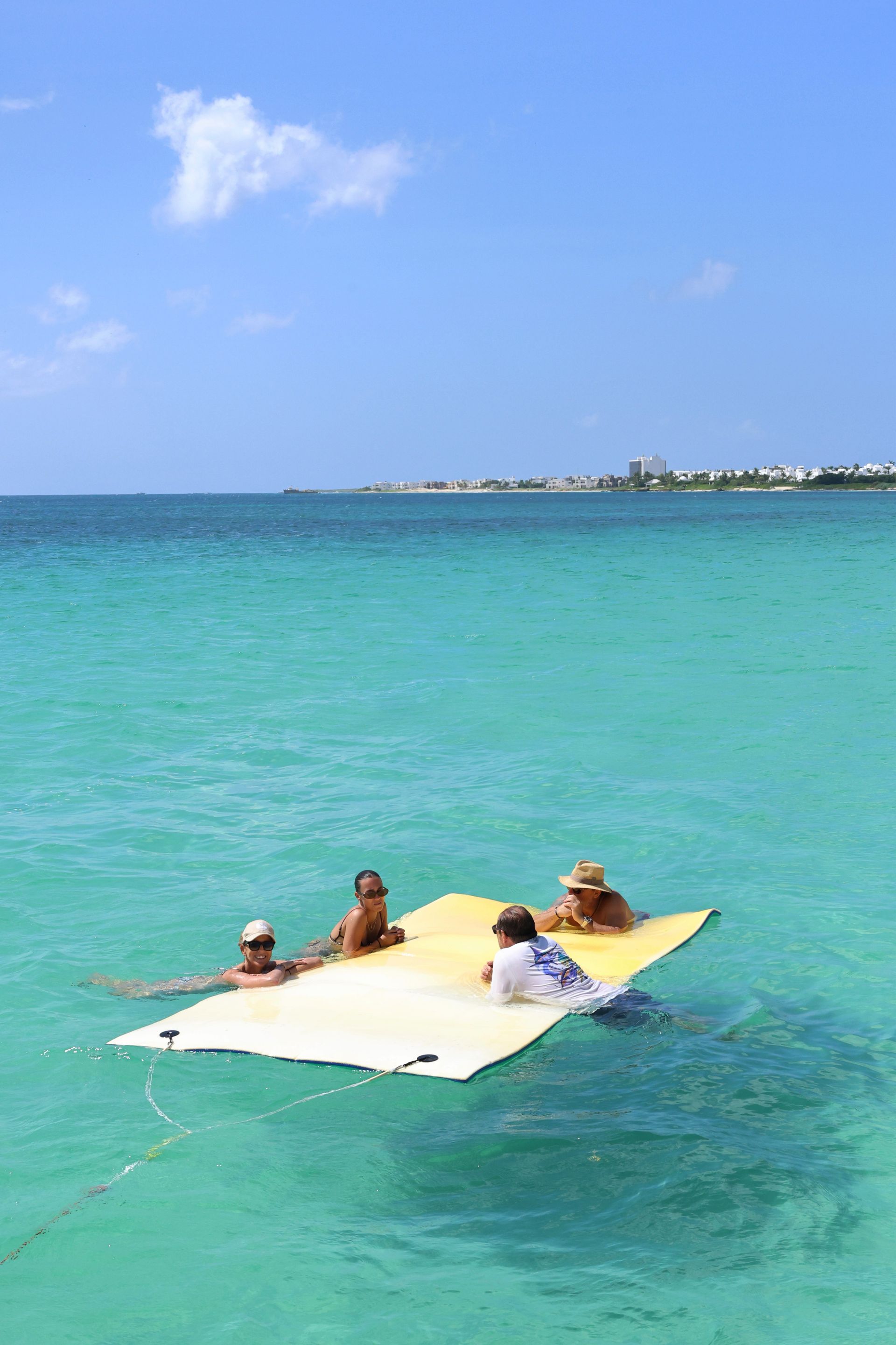 Arawak boat charters in blue sea with guests on mattress, swimming in crystal blue sea at Anguilla