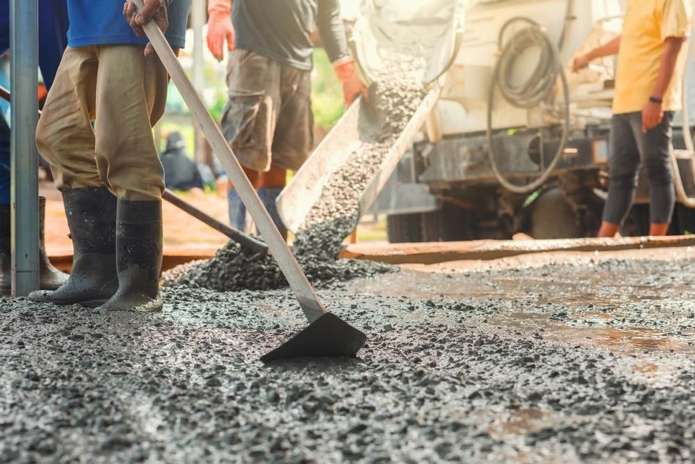 Construction workers paving fresh asphalt with shovels at a roadwork site