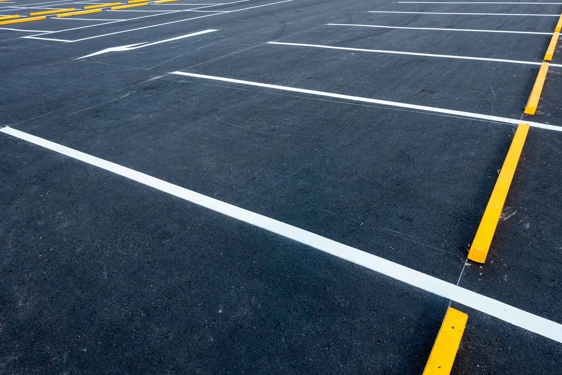 Empty parking lot with white and yellow painted lines on dark pavement
