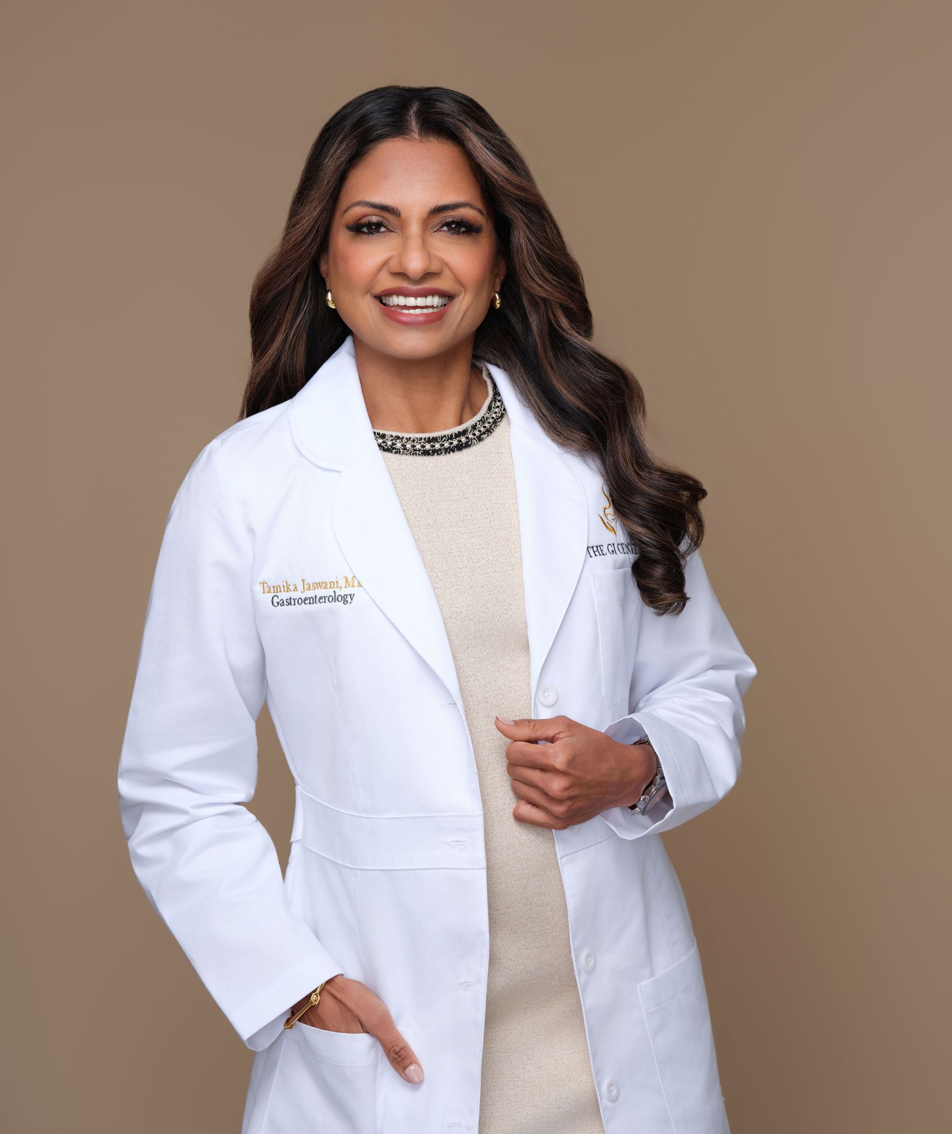 Dr. Tamika Jaswani in white lab coat smiles, stands indoors.