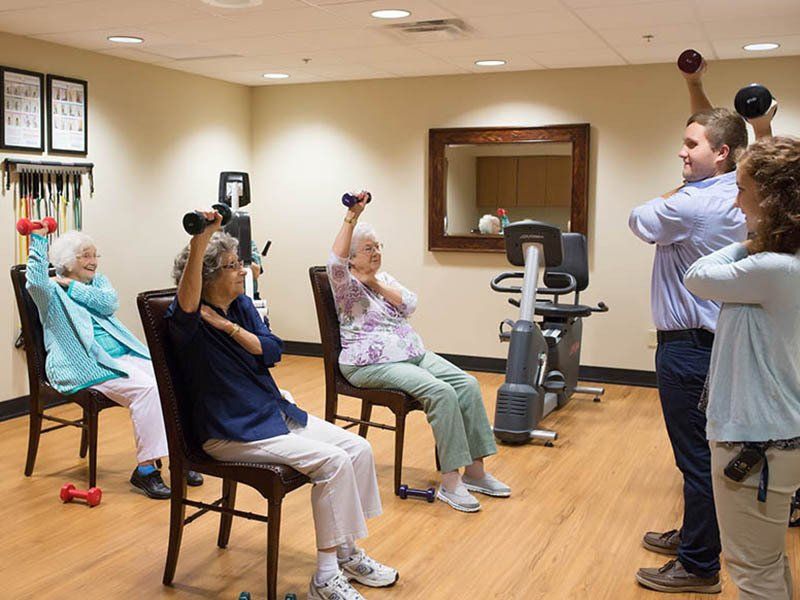 People exercising with dumbbells in a fitness room with an instructor.