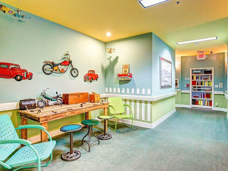 Playroom with car and motorcycle wall decals, work table, and green chairs.