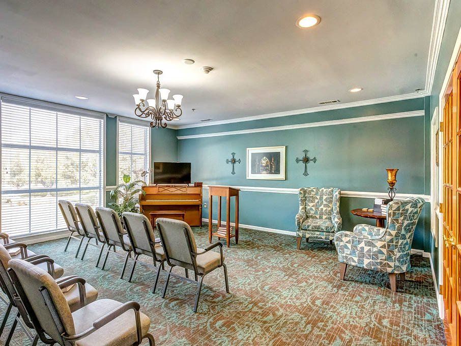 A small chapel with chairs, piano, and a lectern; walls are turquoise with ornate accents.