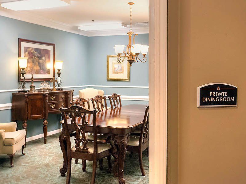 Private dining room with antique furniture, chandelier, and a sign on the right wall.