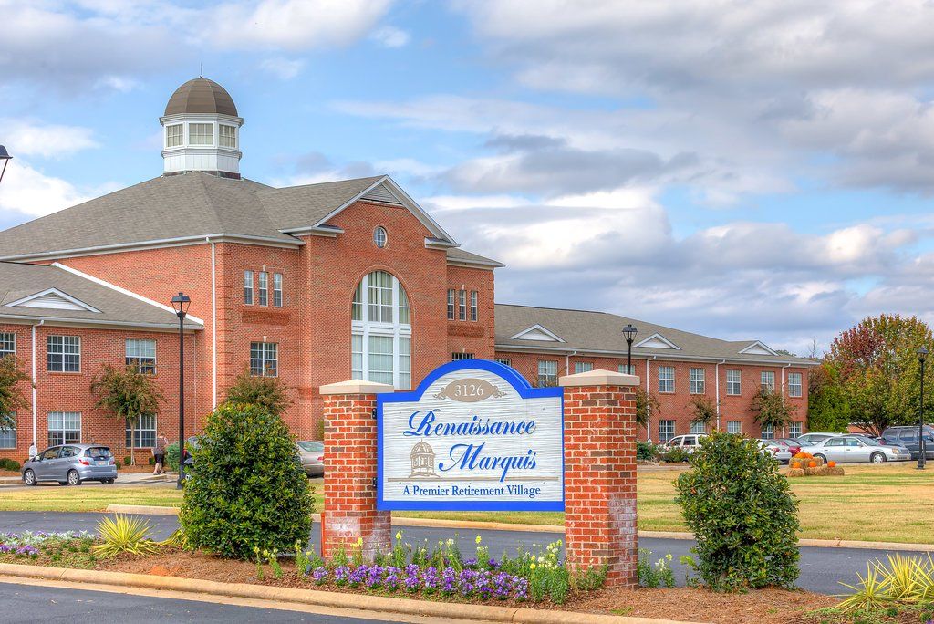 Sign for Bavarian Manor, a senior living community, in front of a brick building under a cloudy sky.