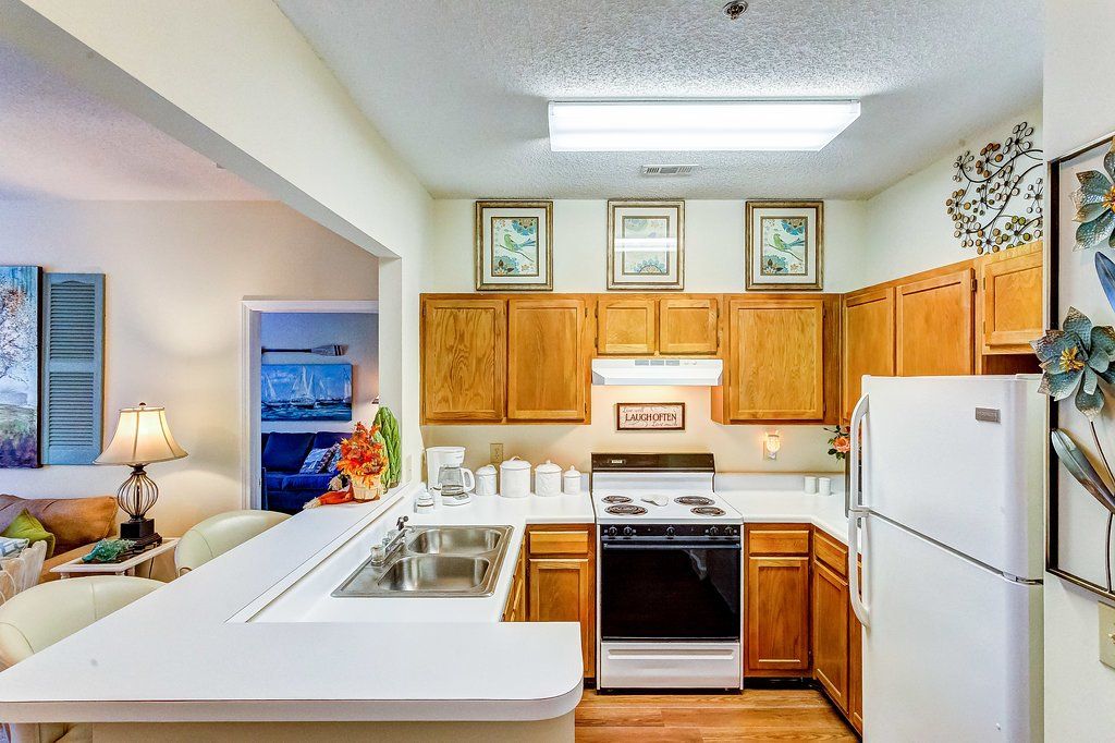 Kitchen with wood cabinets, white appliances, and a breakfast bar.