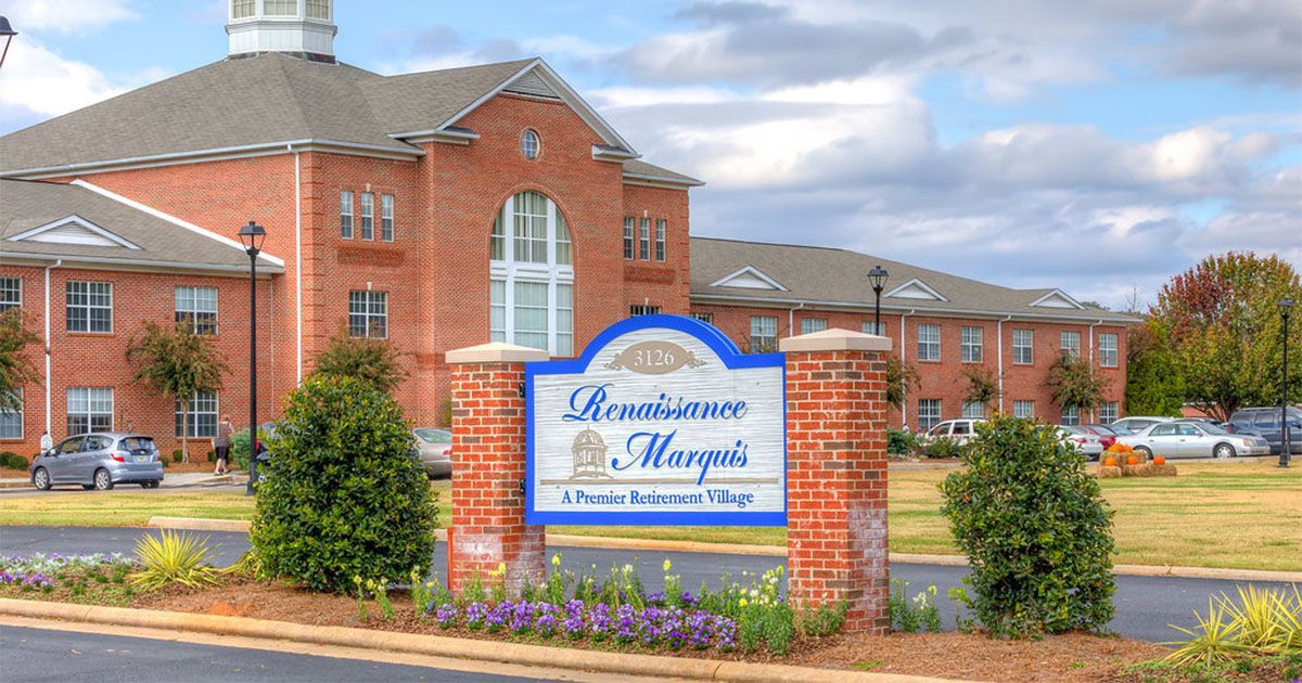 Sign for Savannah Morgan’s assisted living facility. Red brick building with a sign and flowerbeds.