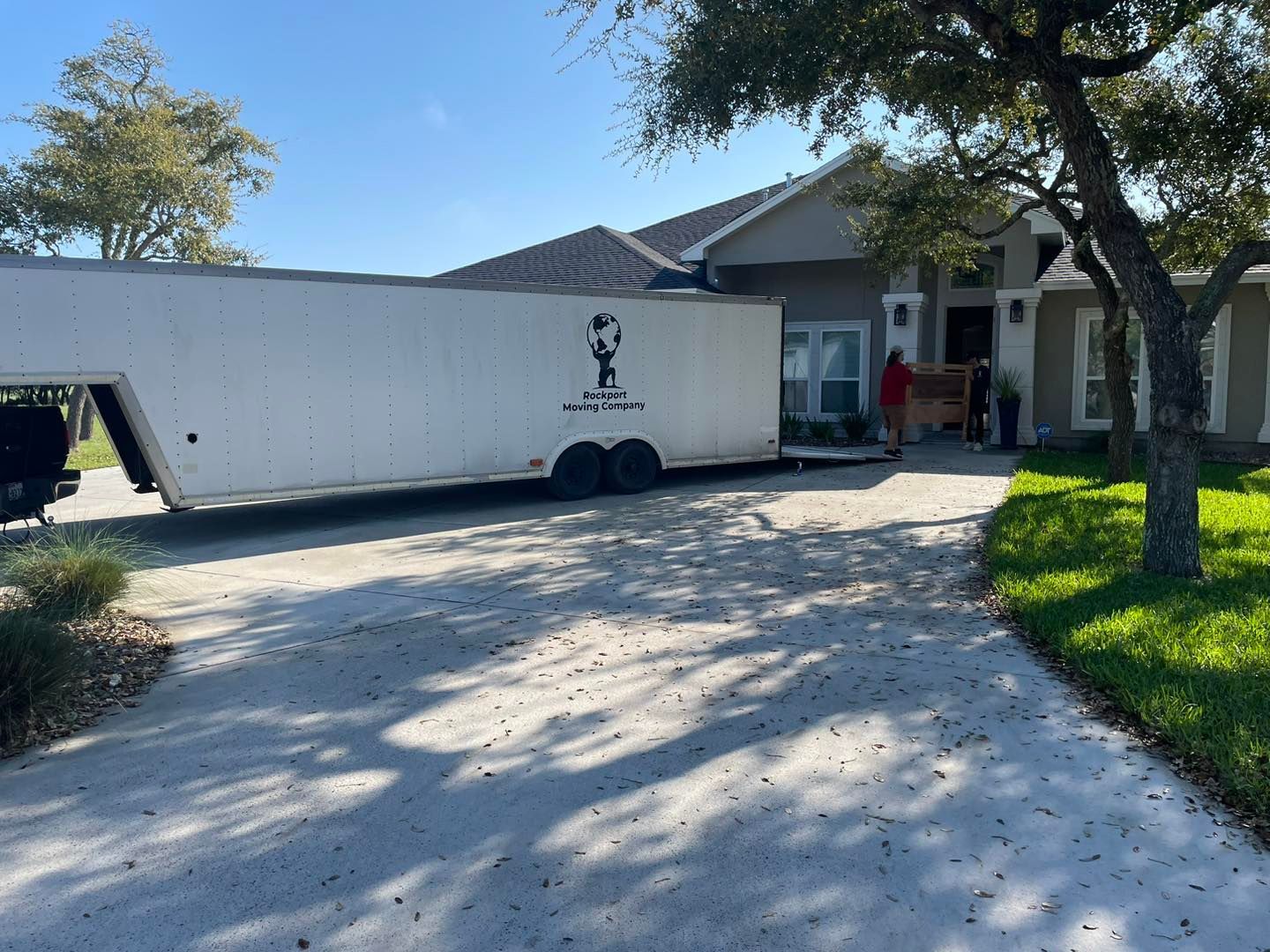Moving truck parked in front of a house; people unloading boxes.