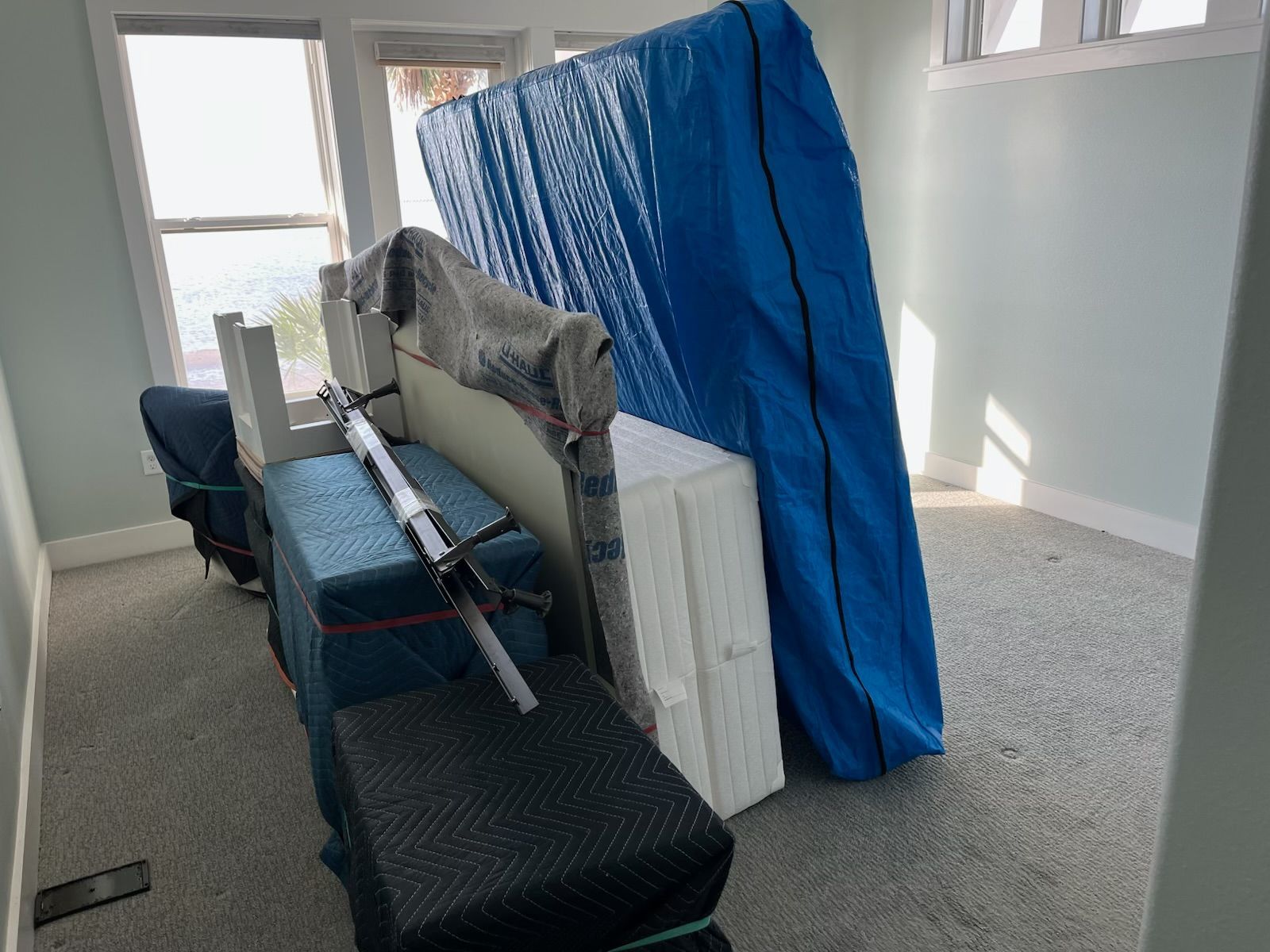 A room filled with furniture wrapped in protective blue covers, ready for moving.