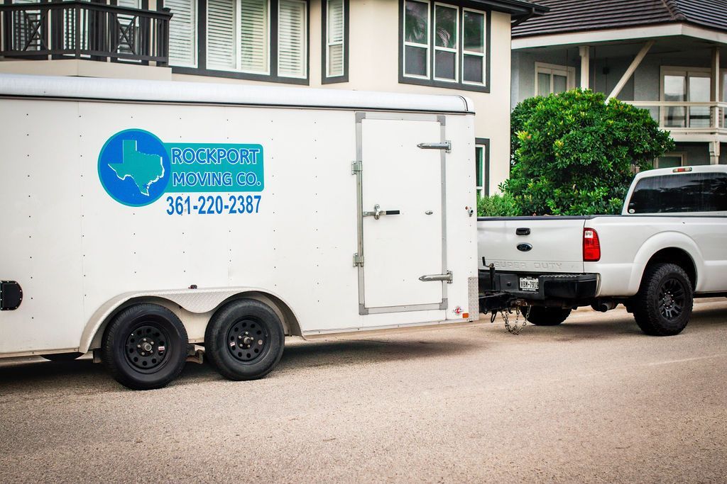 White truck towing a white trailer. Trailer has a blue and green logo and phone number.