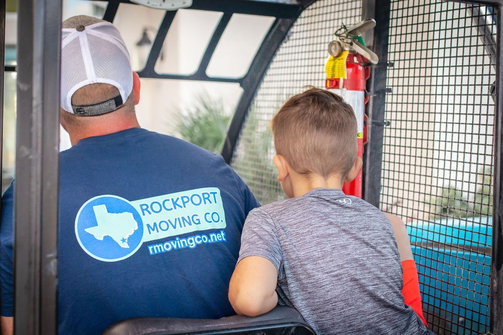 Man in blue shirt with logo, and child, inside a vehicle. A fire extinguisher is visible.
