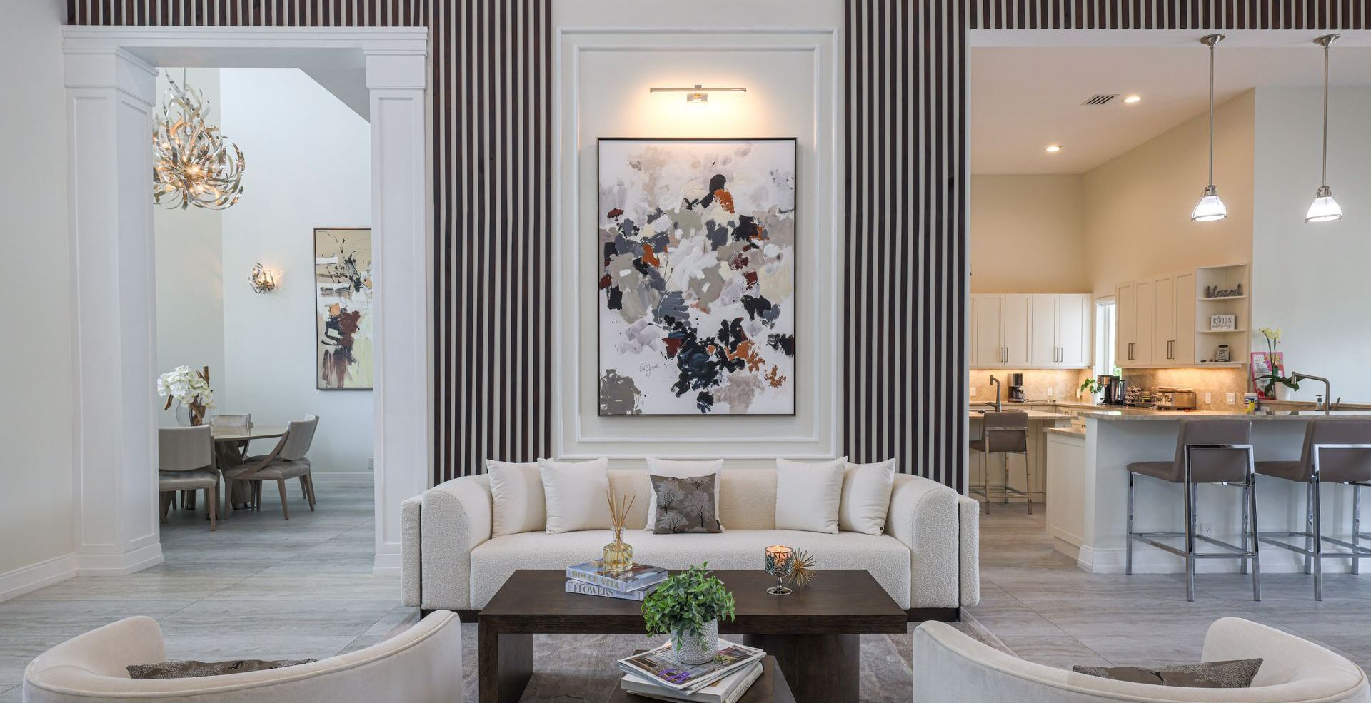Living room with white sofa, artwork, and open doorways to dining and kitchen areas.