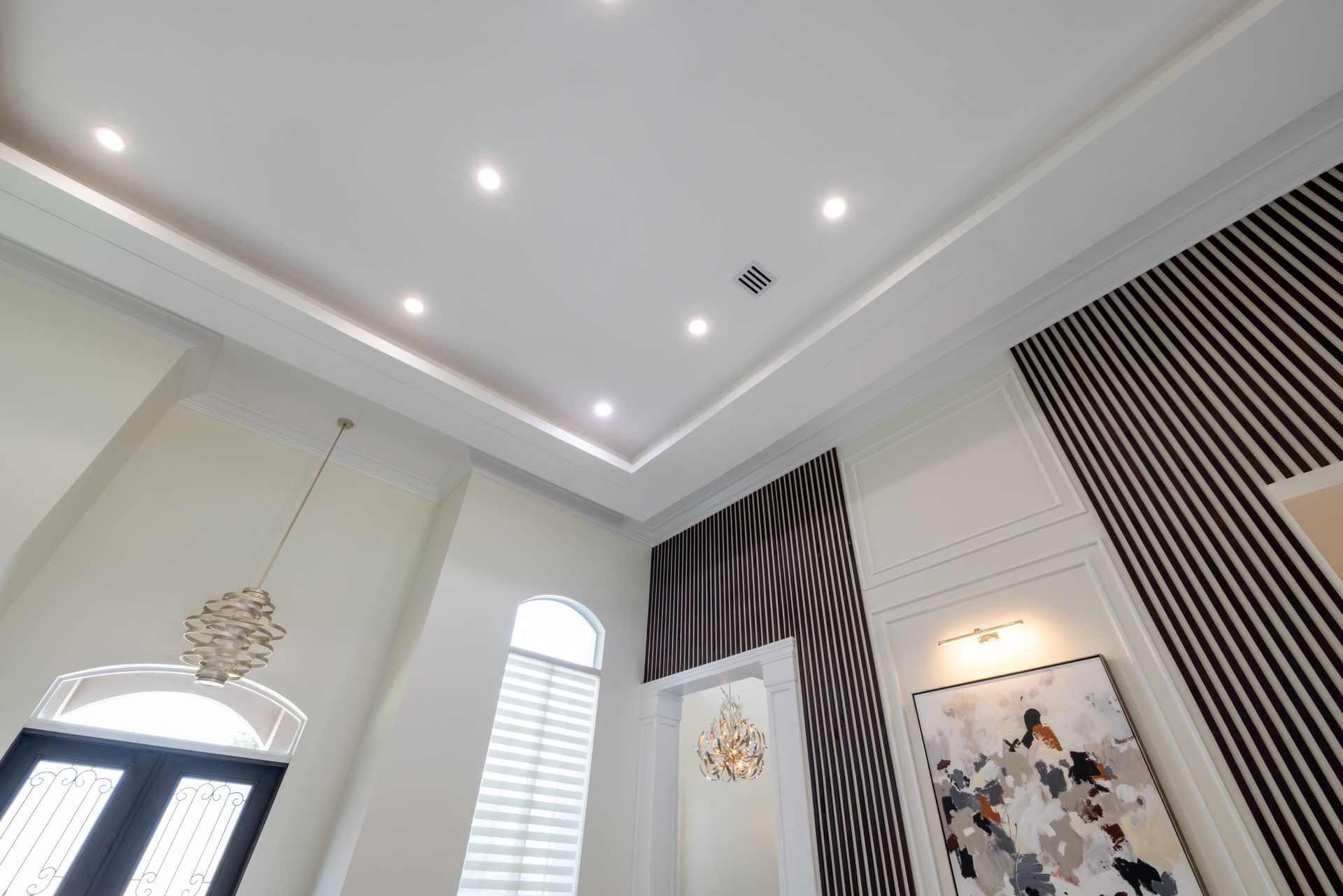 High ceilinged room with white walls, decorative moldings, and black and white striped wall paneling.
