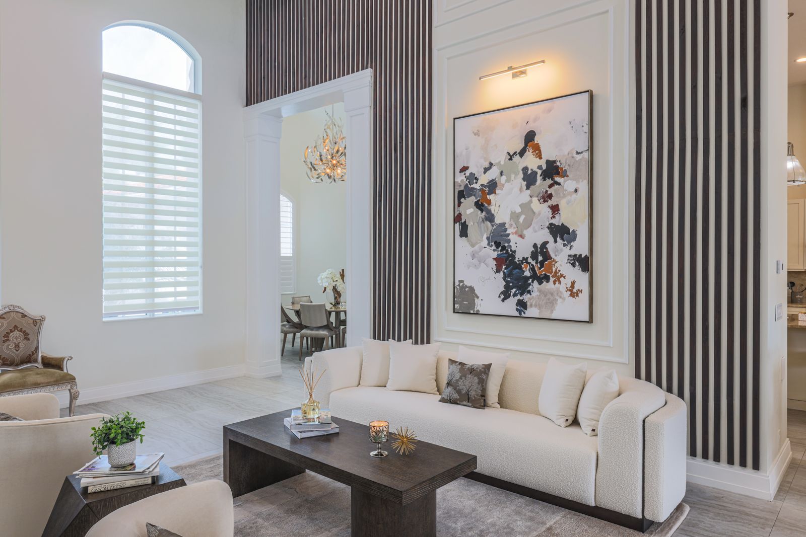 Elegant living room with a modern sofa, abstract art, and vertical wood accents.