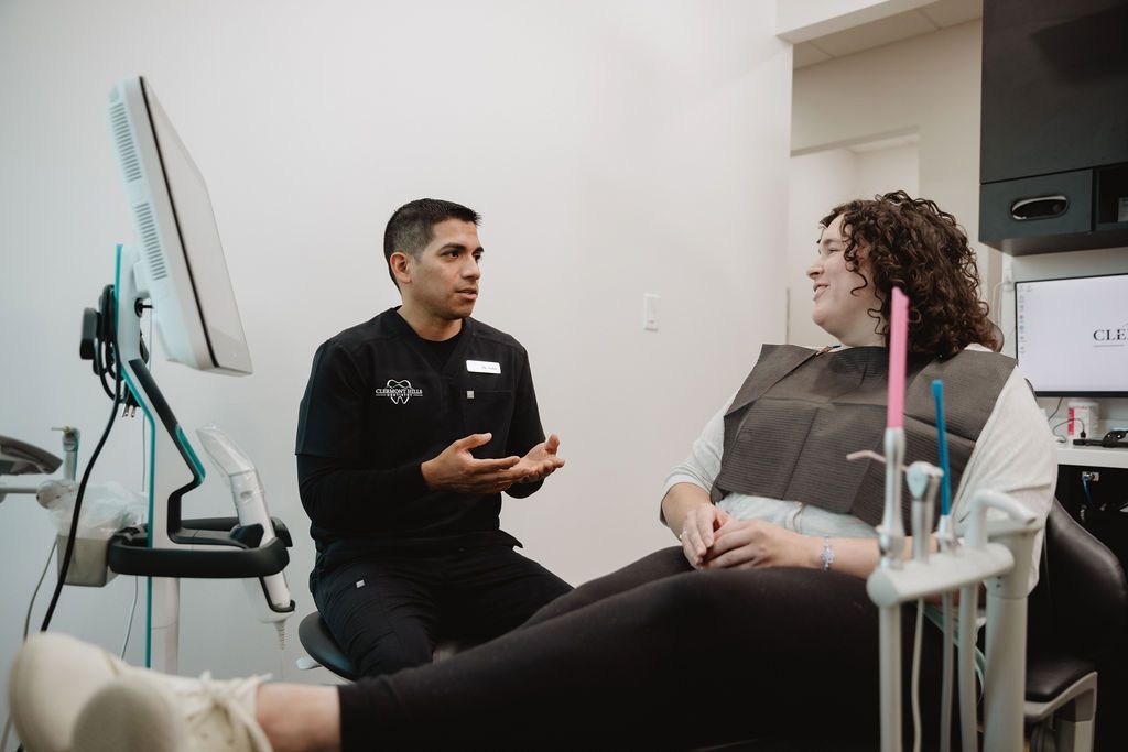 Dentist talking to a patient in a dental office; both are seated.
