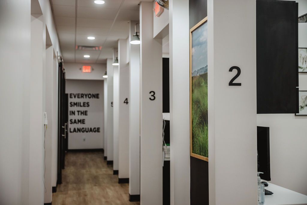 Hallway with numbered columns leading to doors. Artwork, quote on wall: