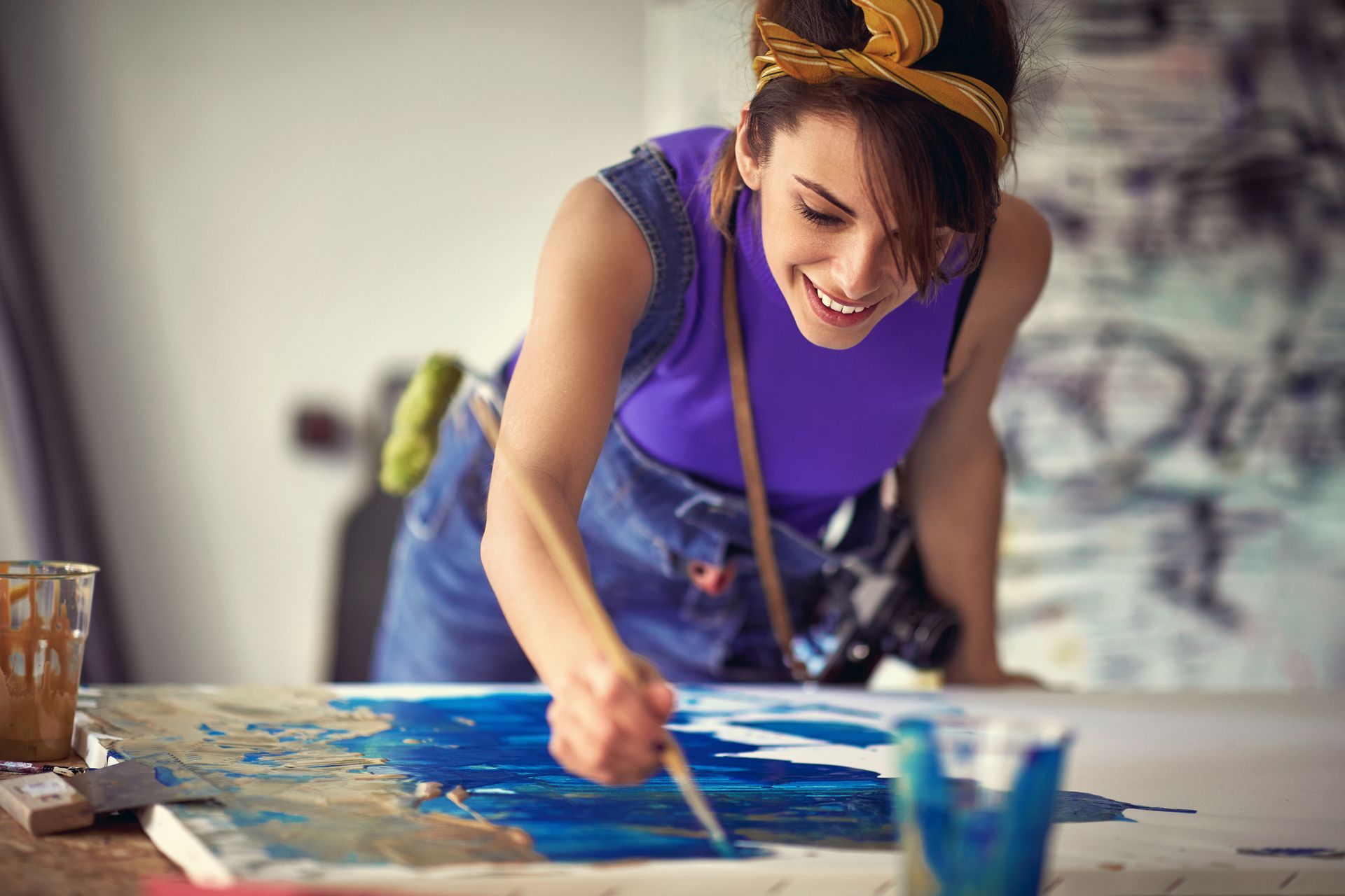 a woman is painting a picture on a canvas with a brush and splatter painting in California