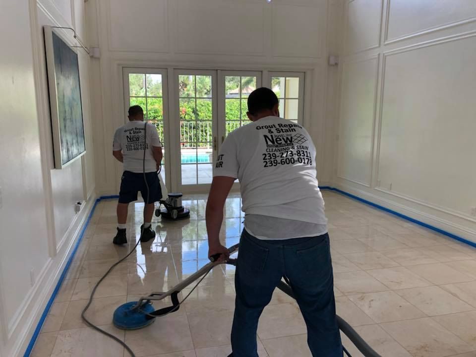 Two men are cleaning a tile floor with a vacuum cleaner.